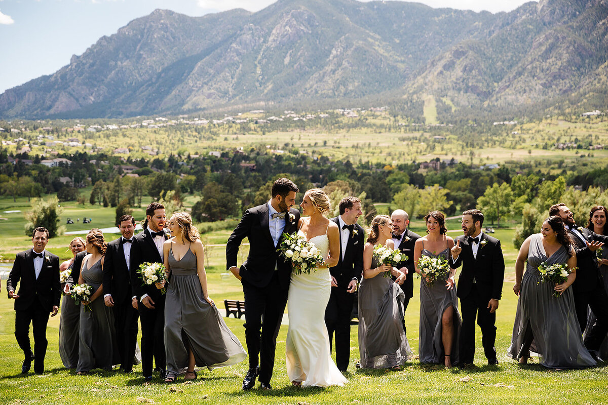 Bride and groom walk with their wedding party with bridesmaids in grey dresses in Colorado Springs, Colorado.