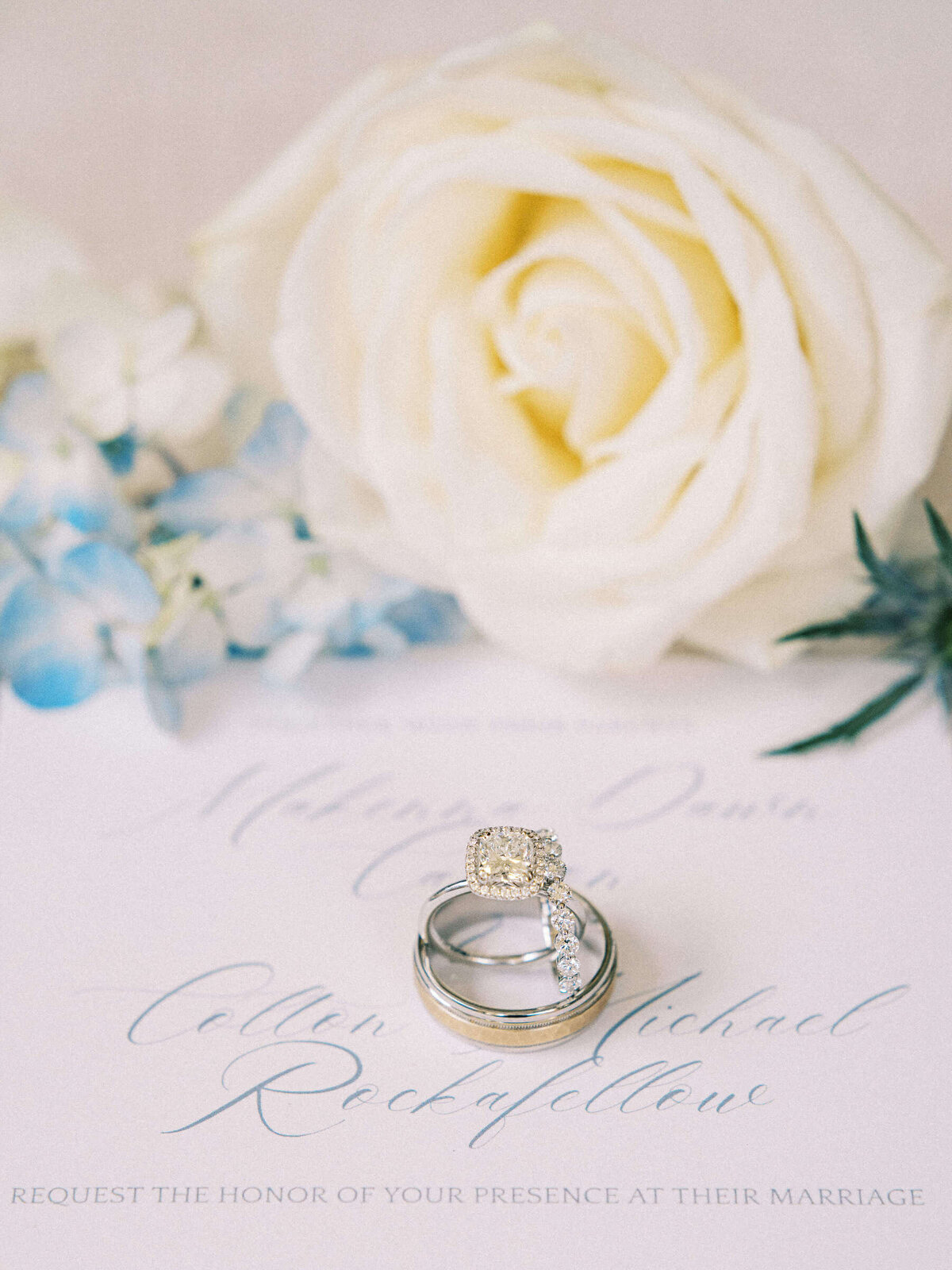 Bride and groom's rings showcased on wedding suite with white rose