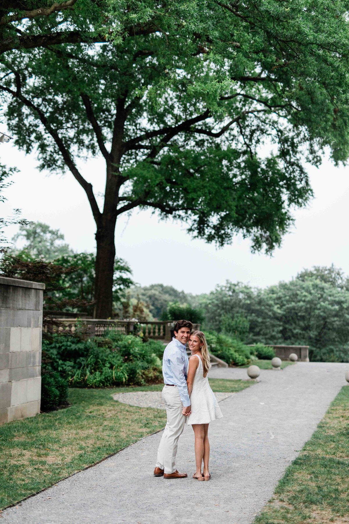 Couple walking away and turning around, man wearing blue shirt and tan pants, girl wearing short white dress