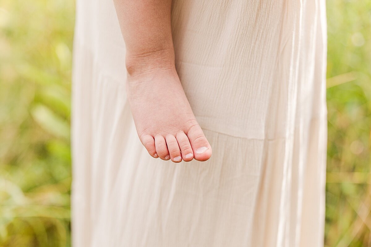 girls foot by mom's dress during outdoor newborn photo session with Sara Sniderman Photography at Heard Farm in Wayland Massachusetts