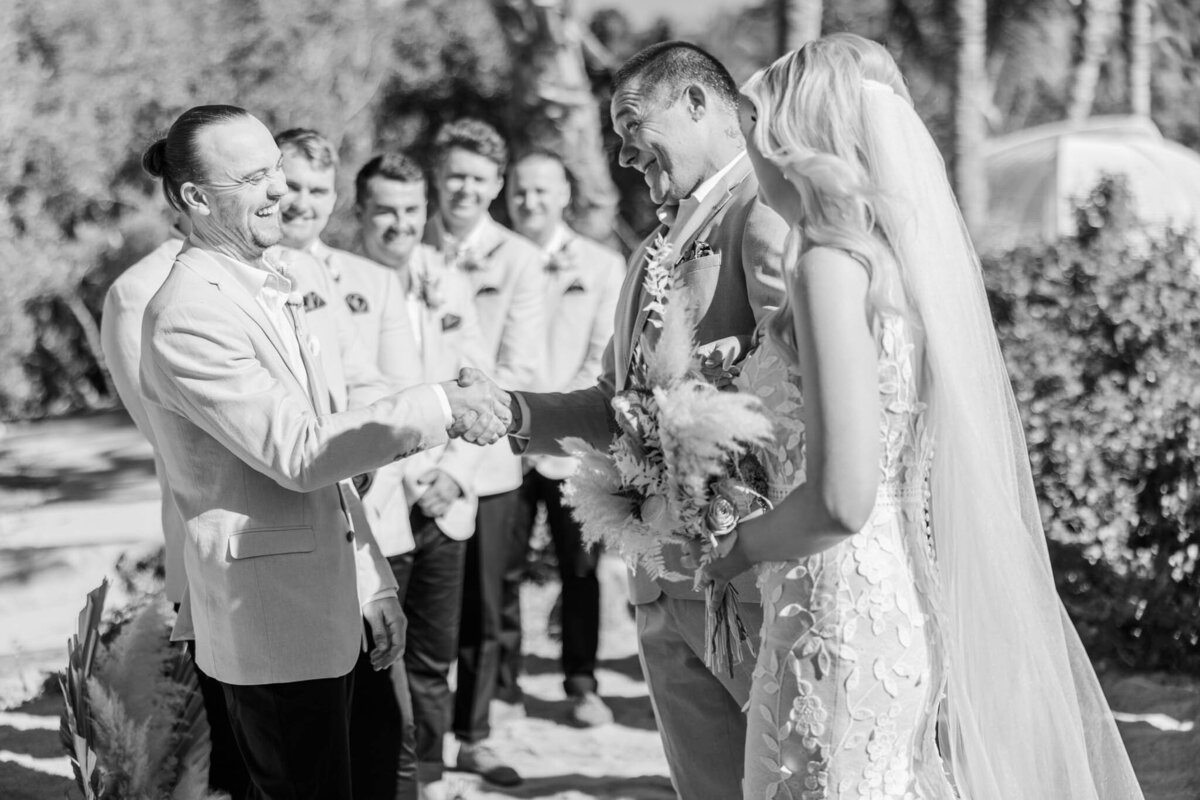 Father of the bride shakes hand with the groom on their wedding day in Airlie beach