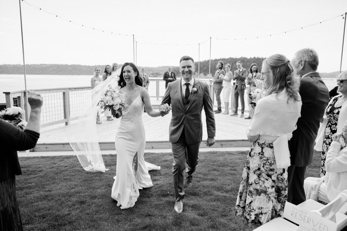 Bride and groom laughing as they walk down the aisle