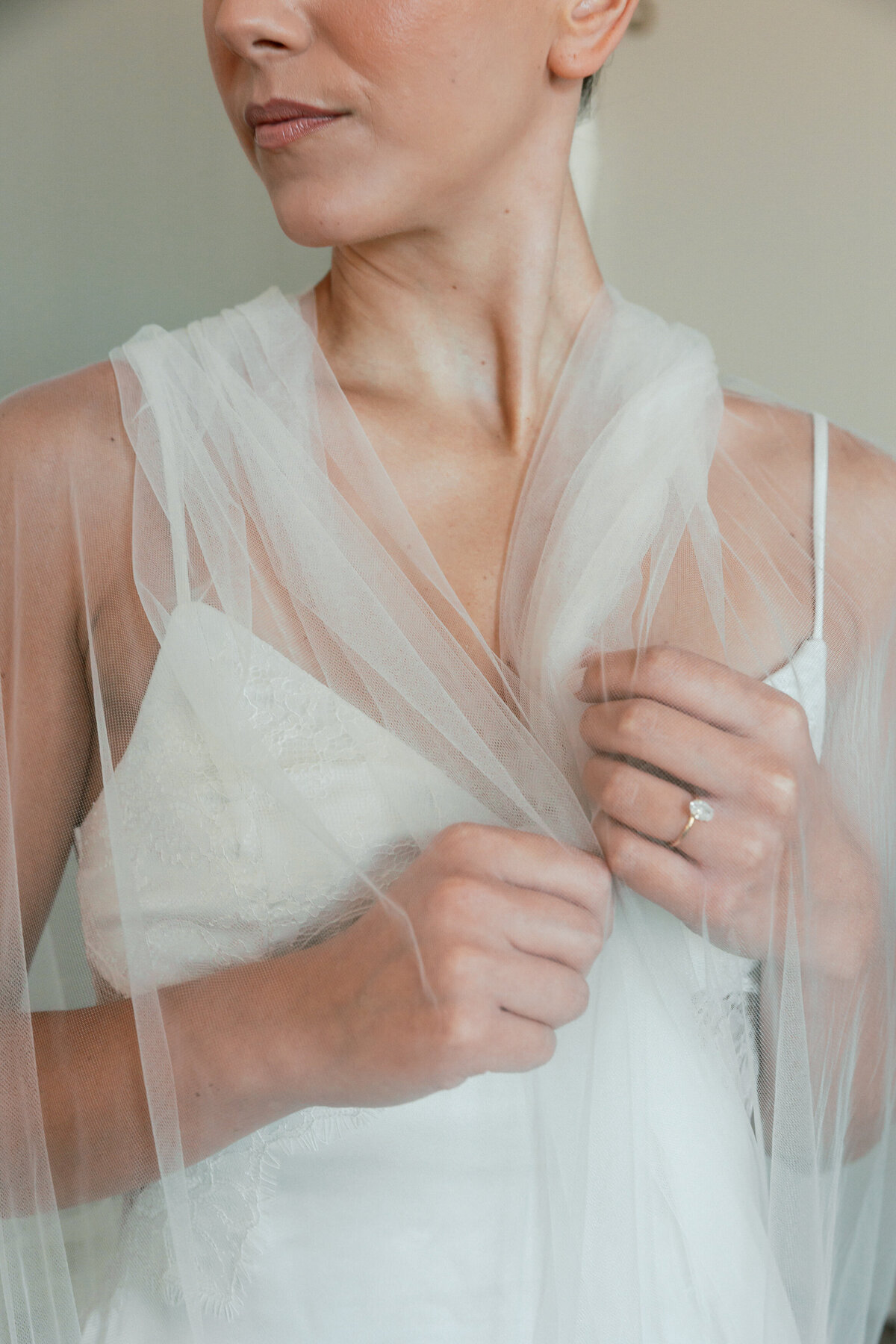 Close-up of bride adjusting her tulle veil, featuring her engagement ring, captured by a Philadelphia wedding photographer.