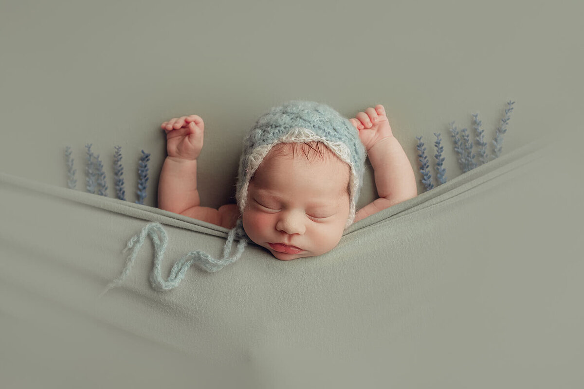 baby girl sleeping with arms up with blue flowers