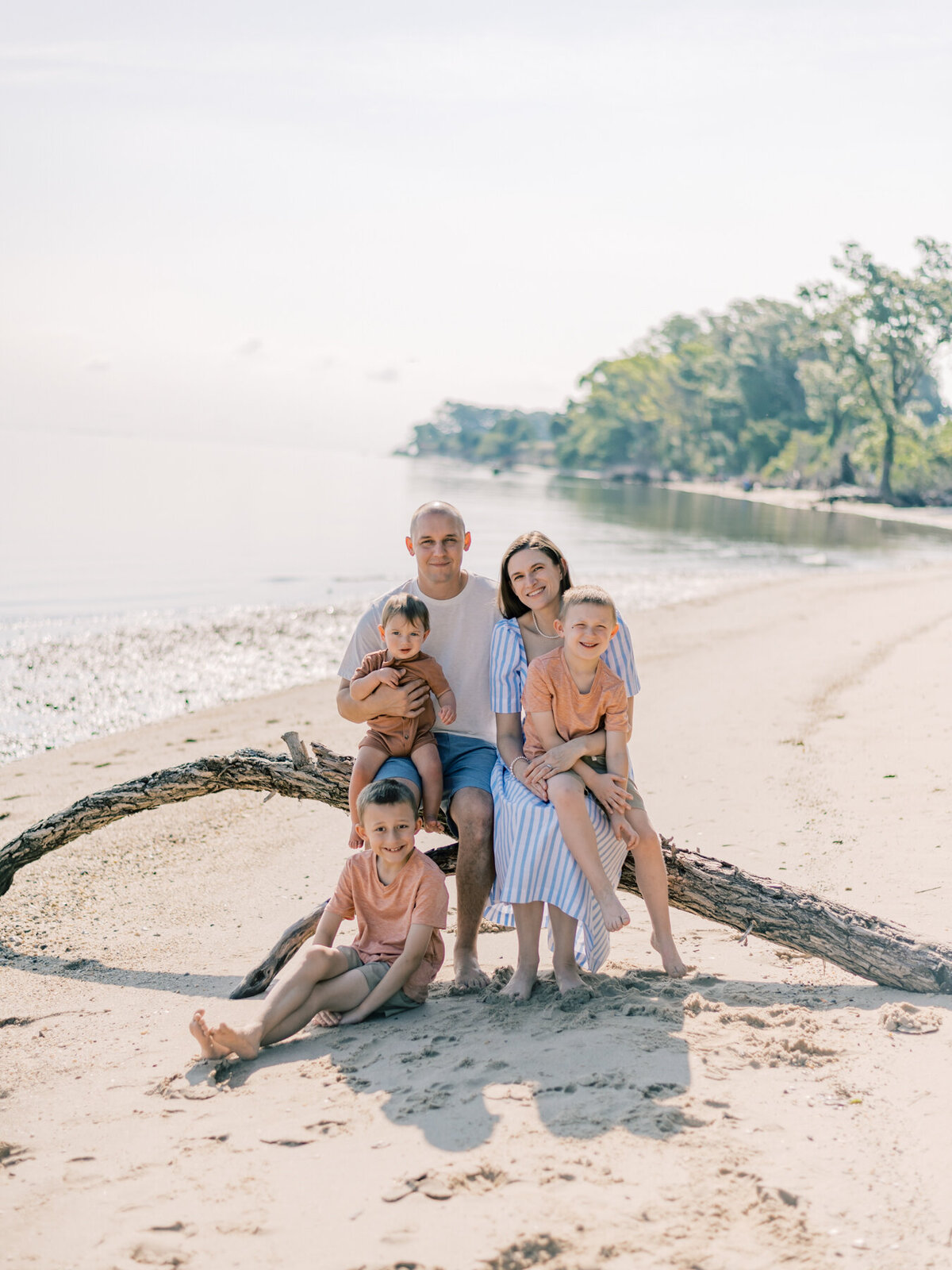 Family sitting on driftwood during family session