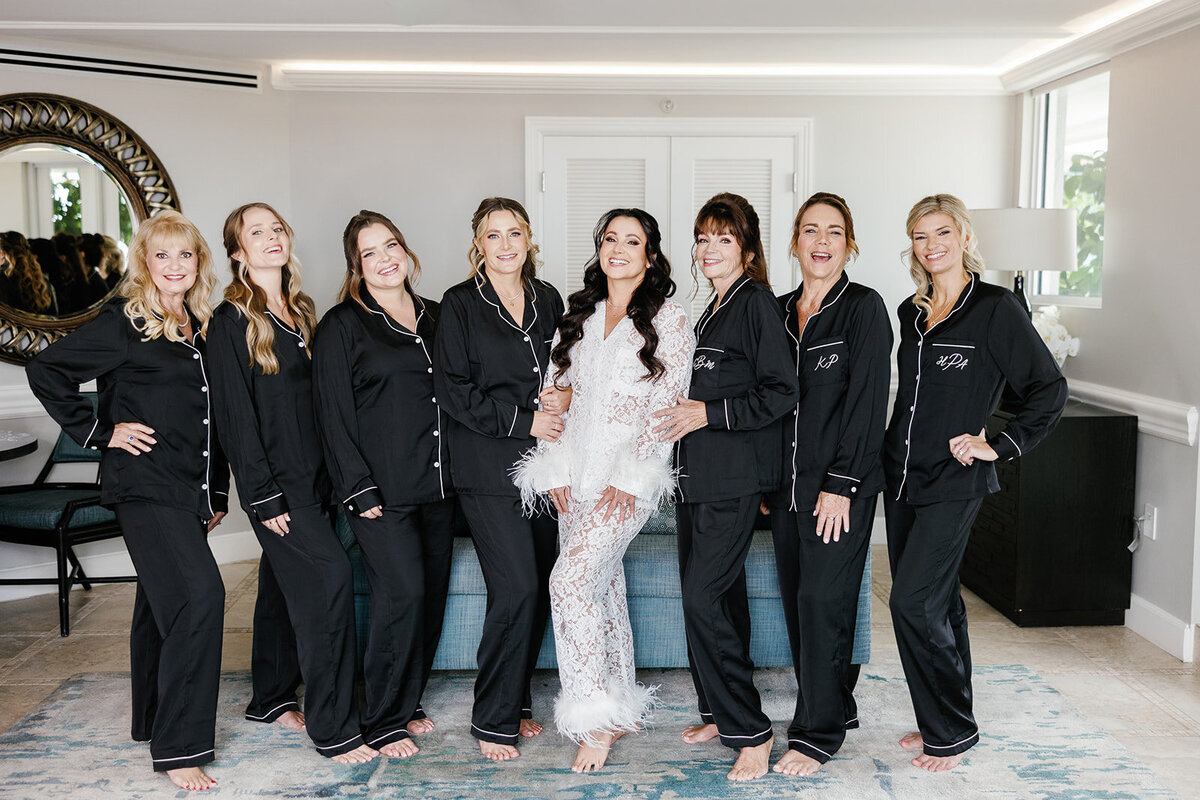 The bride and her bridesmaids in matching black pajamas posing and smiling during the getting-ready moments at Ashley and Cameron's micro wedding at Ocean Reef in Key Largo, captured by Claudia Amalia Photography.