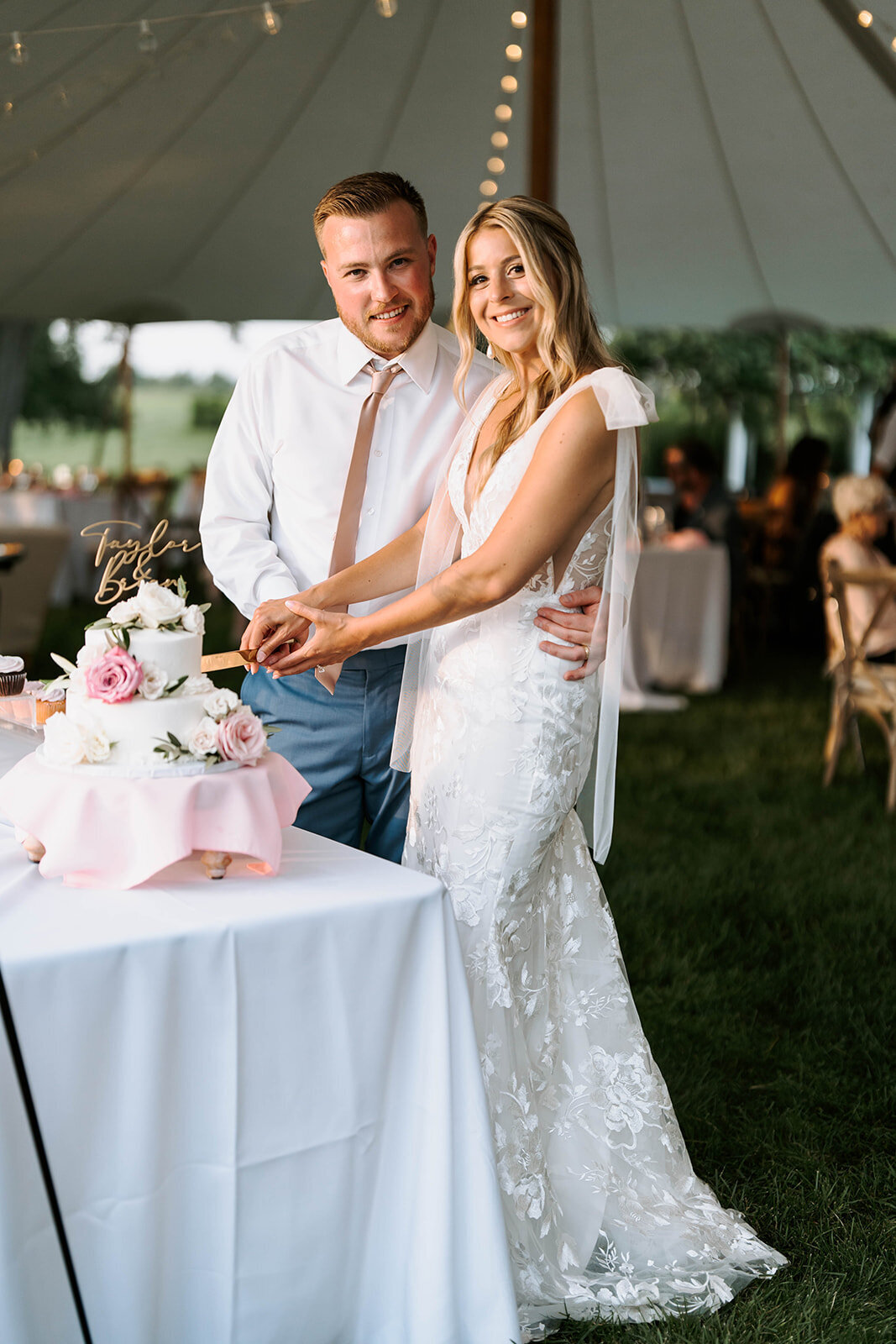 quiet cake cutting in tented wedding reception with blush and white decor