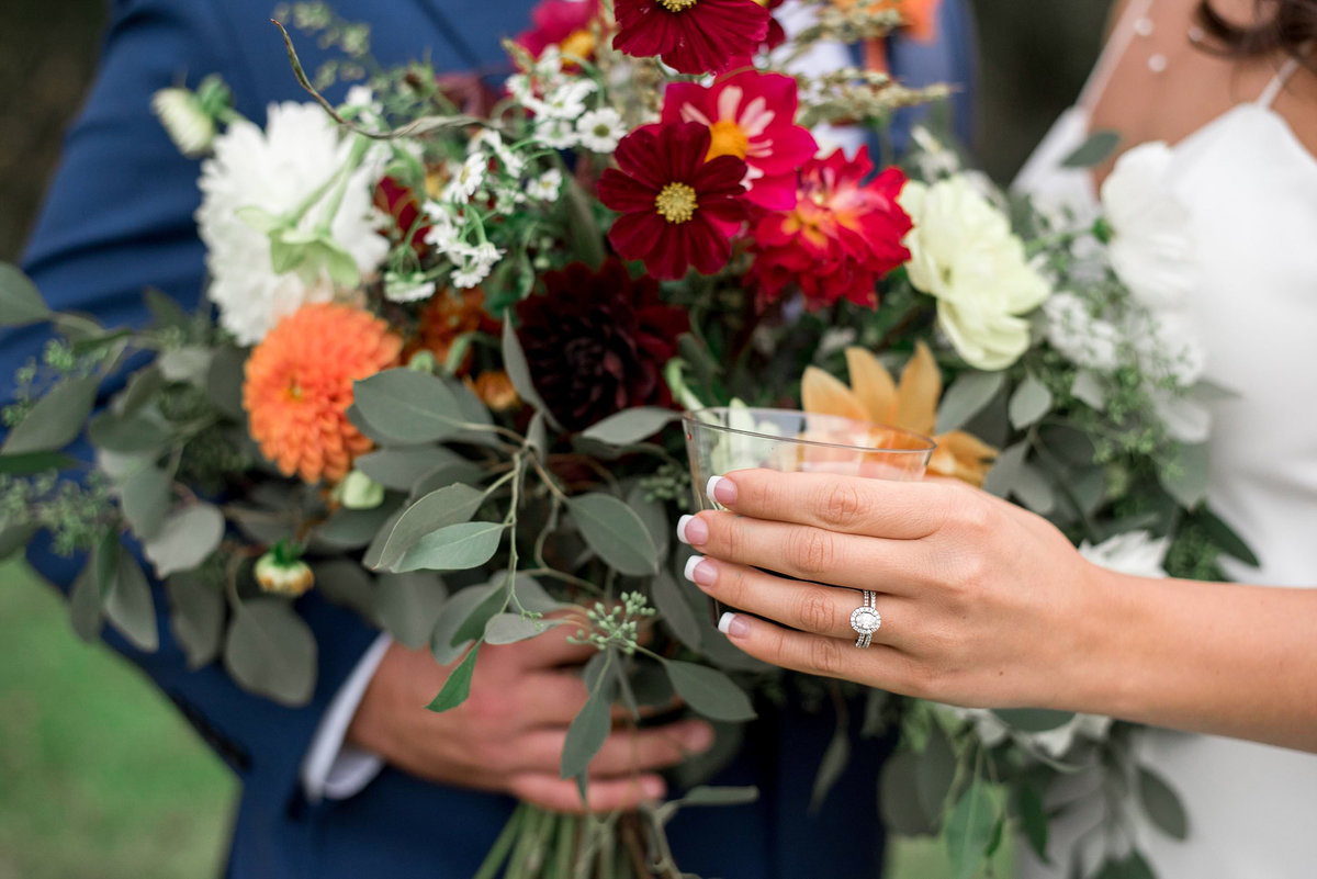 Detail photo of bride holding wine glass next to her wildflower bouquet
