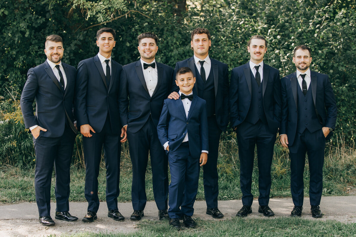 Groom posing with his groomsmen in their matching blue suits