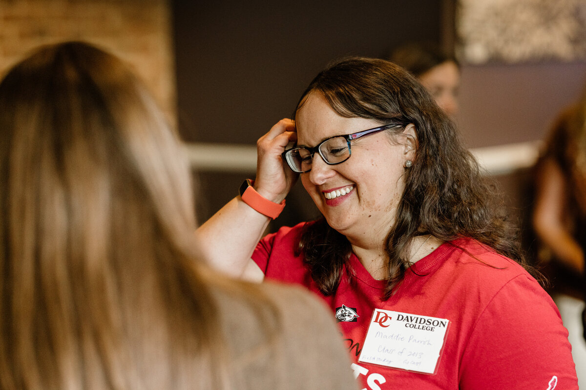 Candid moment of a guest at an event smiling while interacting with colleagues. 