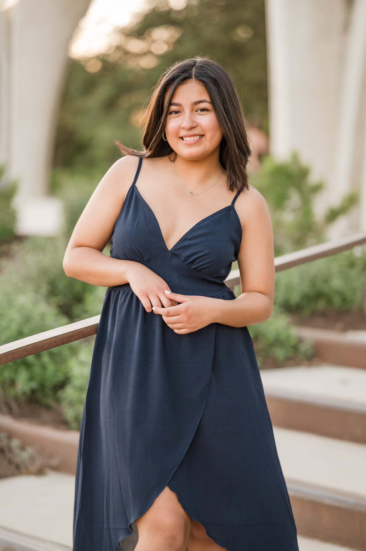 San Antonio senior girl poses for pictures in a blue dress  in golden hour light.