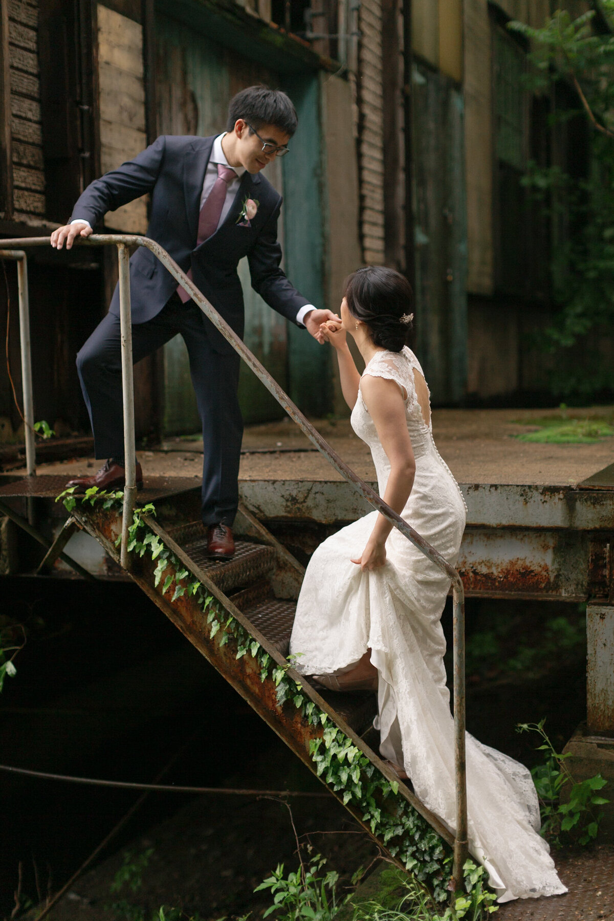 Elegant bride climbing ivy-covered stairs to the groom.
