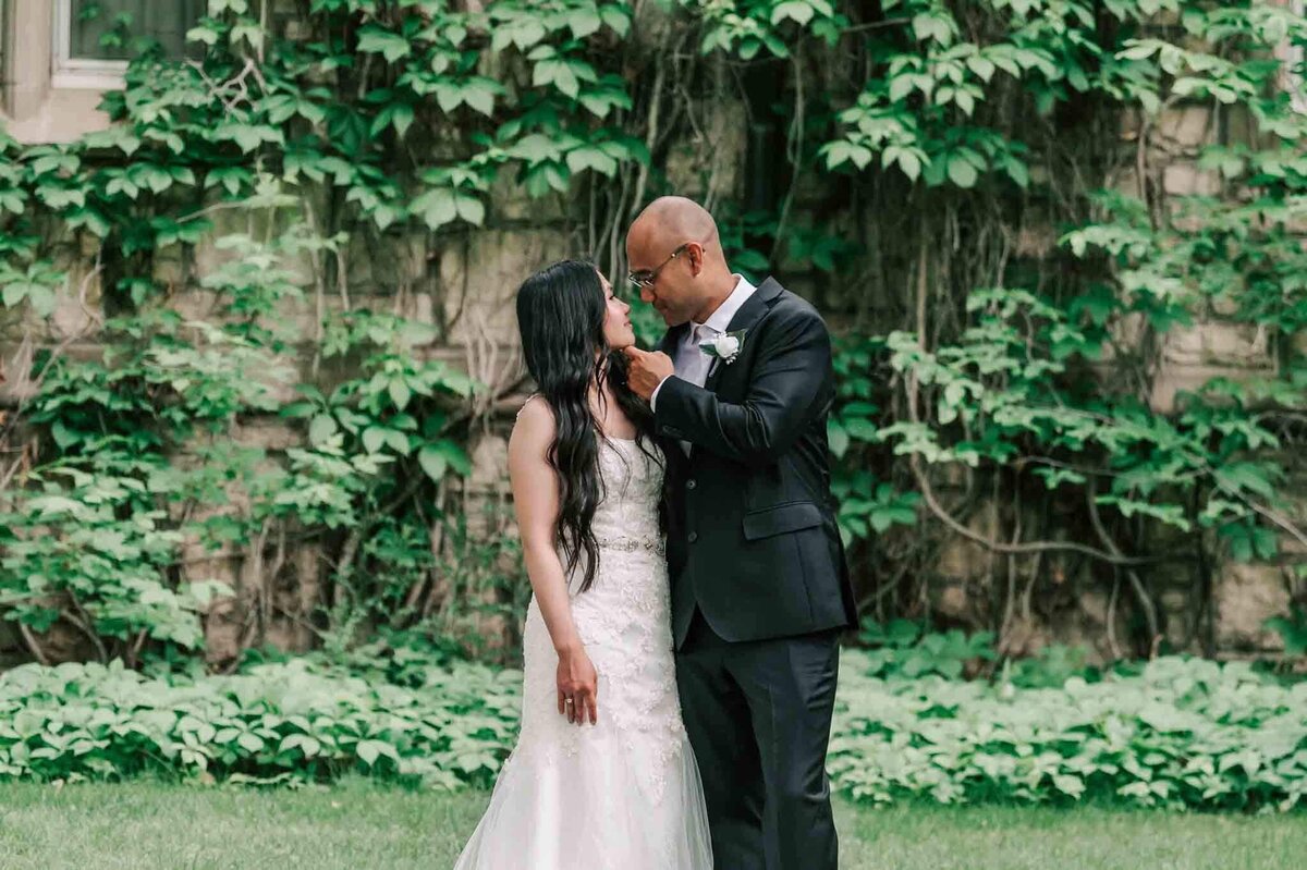 Bride and groom standing beside each other and looking into their eyes. Groom has his hand on her face.