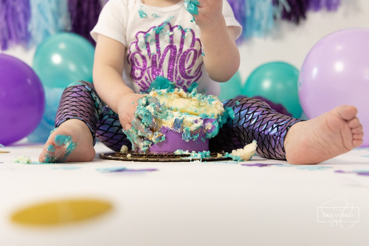 One year old girl eating birthday cake