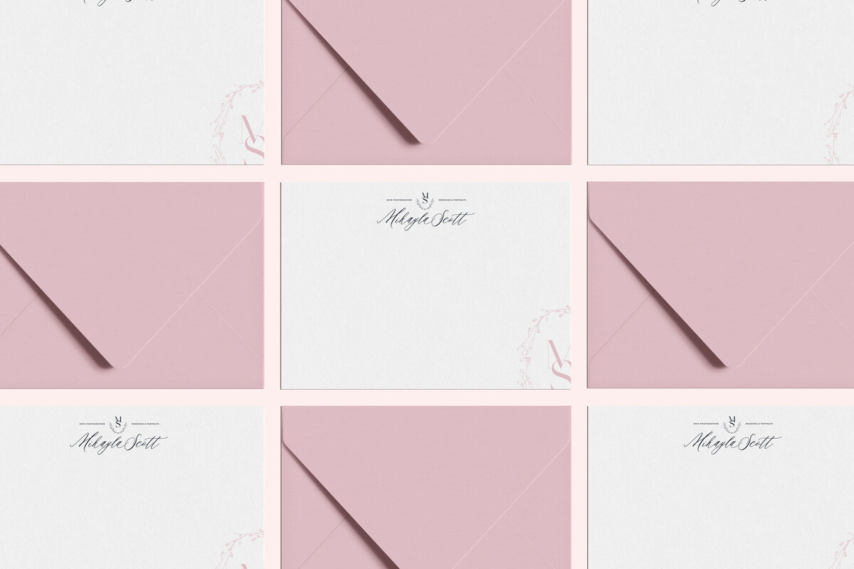 a mockup of a black logo on white stationery with pink envelopes