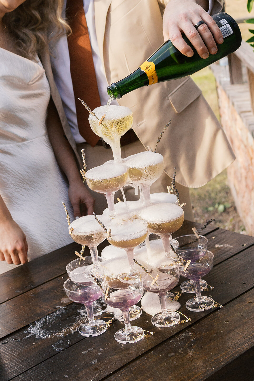 Close up of bride and groom pouring a champagne tower