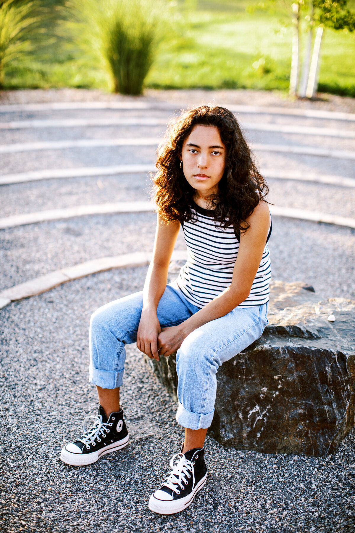 girl in striped tank top sits in circular maze