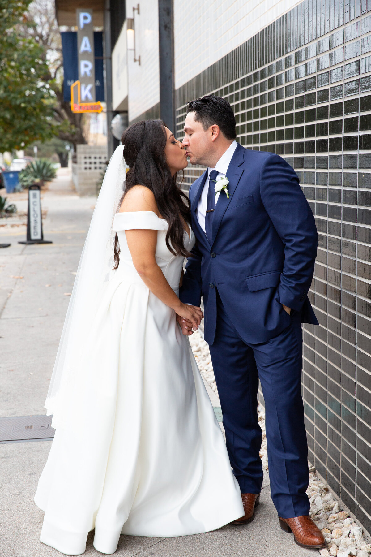 A bride and groom captured by an Austin wedding photographer, sharing a passionate kiss in front of a stunning building.