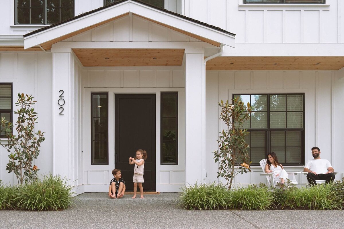 family of four at white house on porch