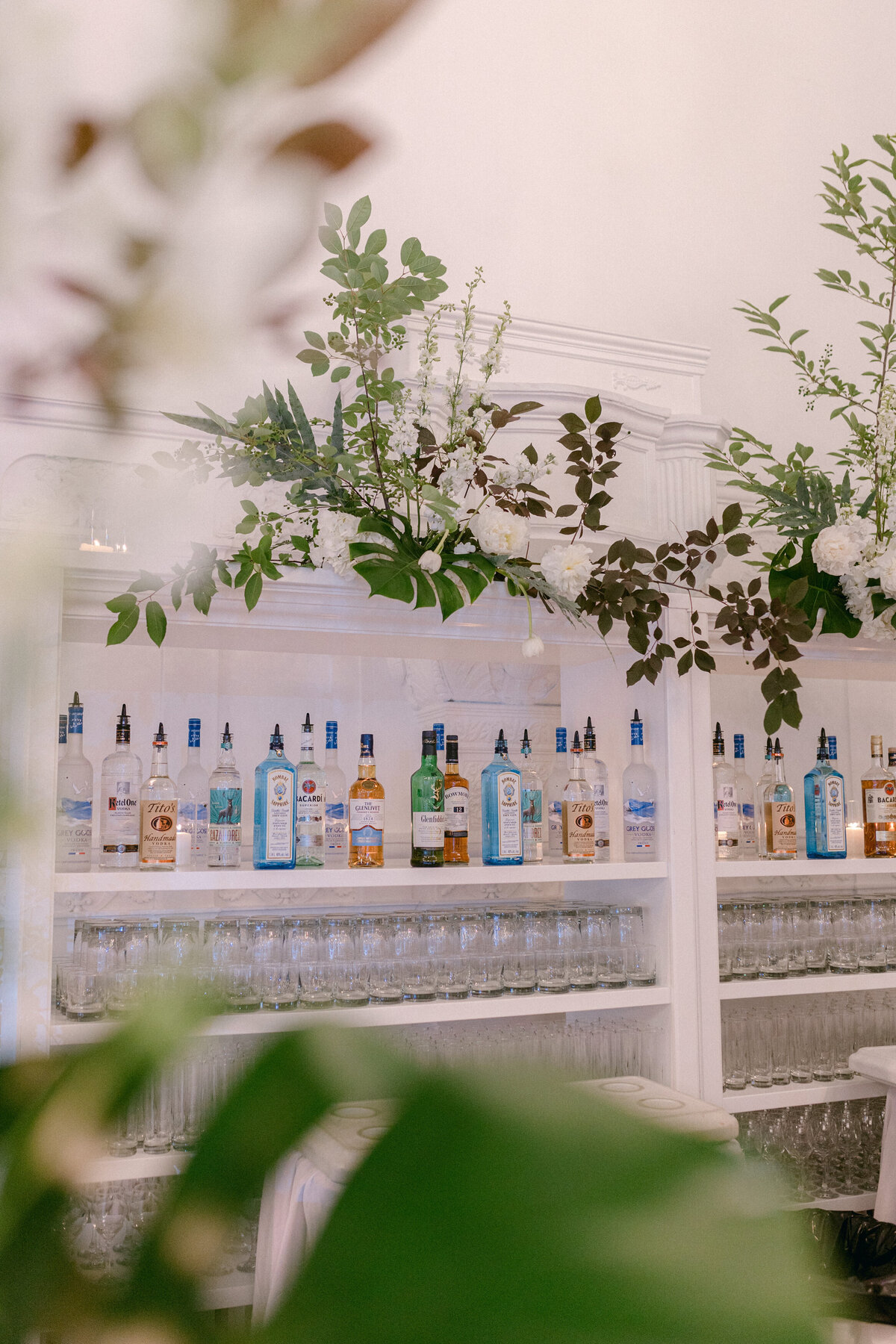 A wedding reception barback is decorated with textured organic greenery at Maison Principale.