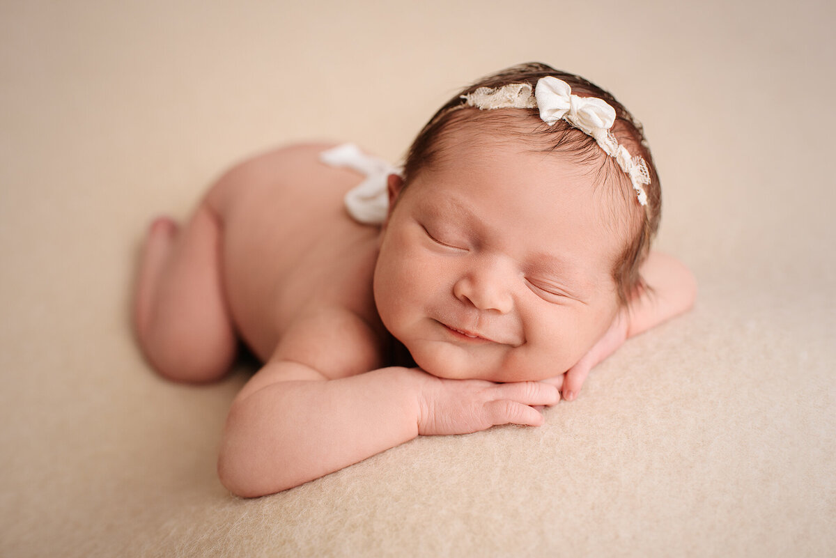 In home studio newborn portrait of baby girl on light backdrop in Jacksonville, FL.