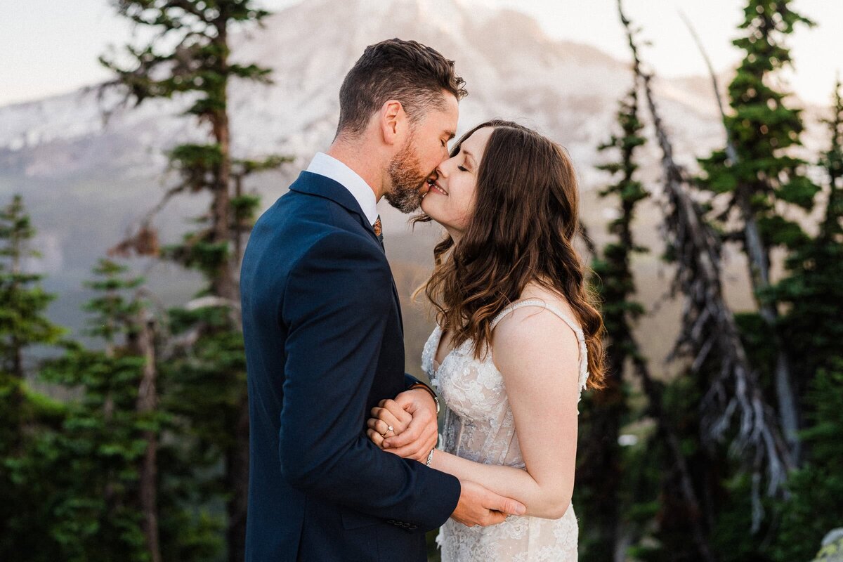 eloping couple kissing  at sunrise in the mountains in front of Mount Rainier.