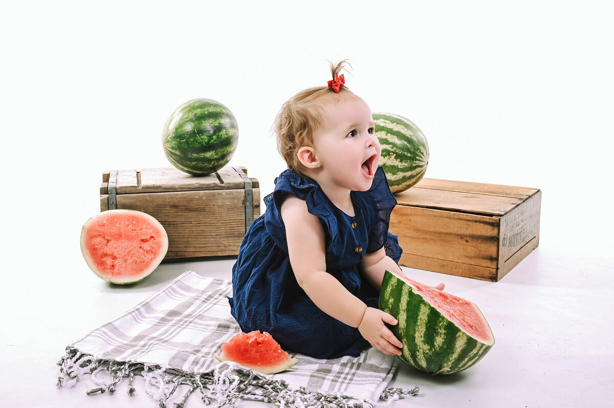 Little girl shouts with excitement as she holds part of a watermelon