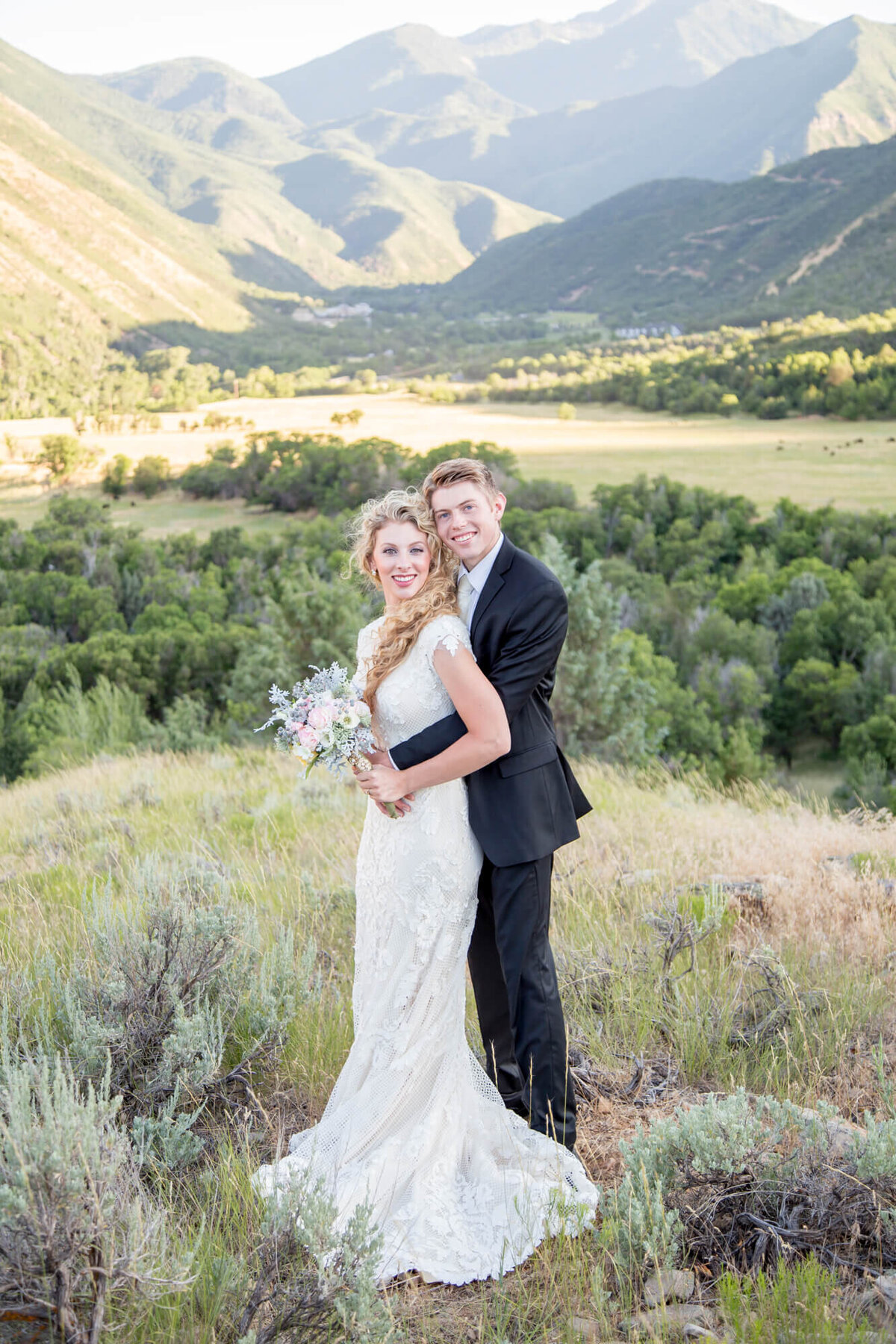 a wedding couple holding each other in the mountains