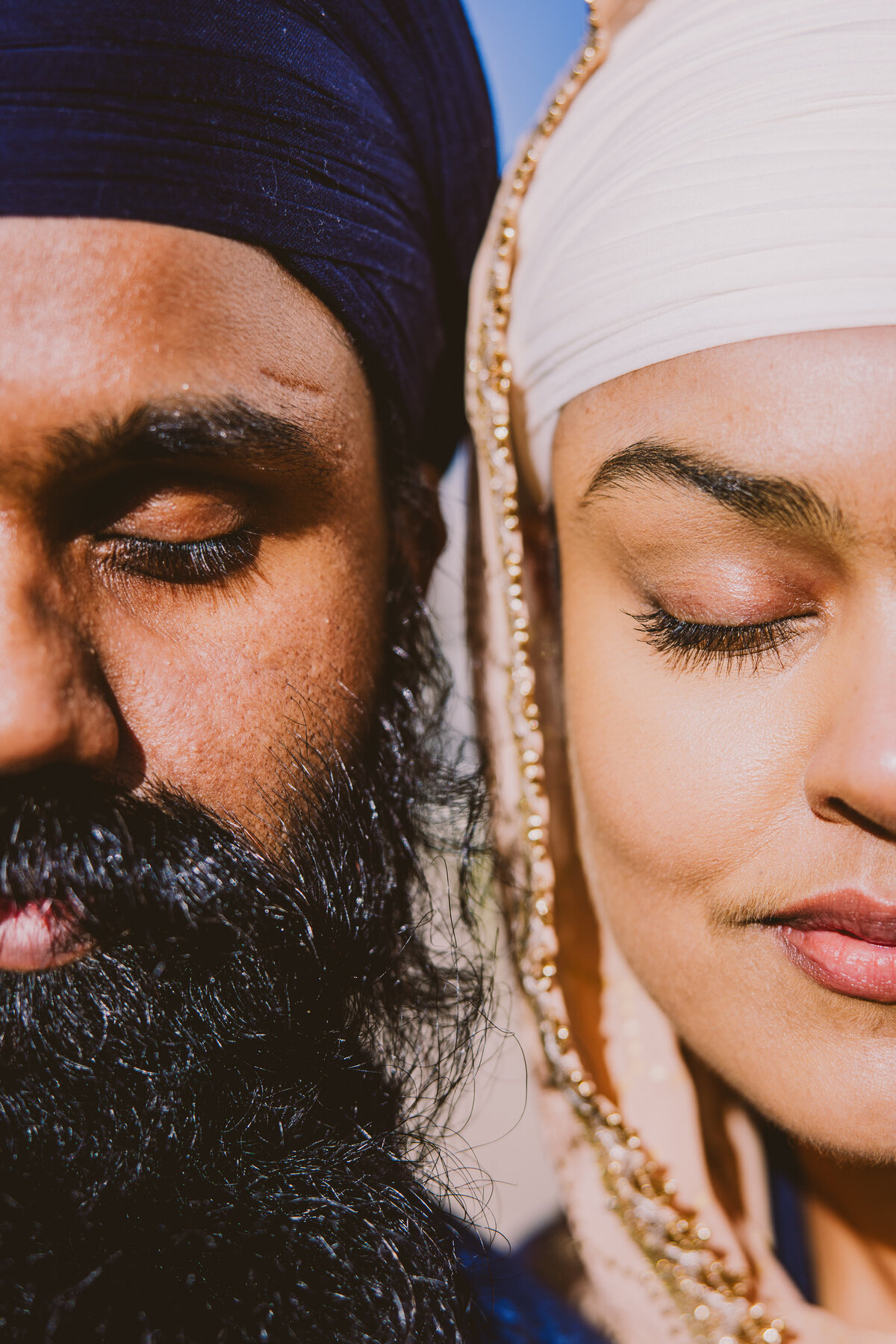 An engaged sikh couple close their eyes and put their faces next to each other in a meditative pose