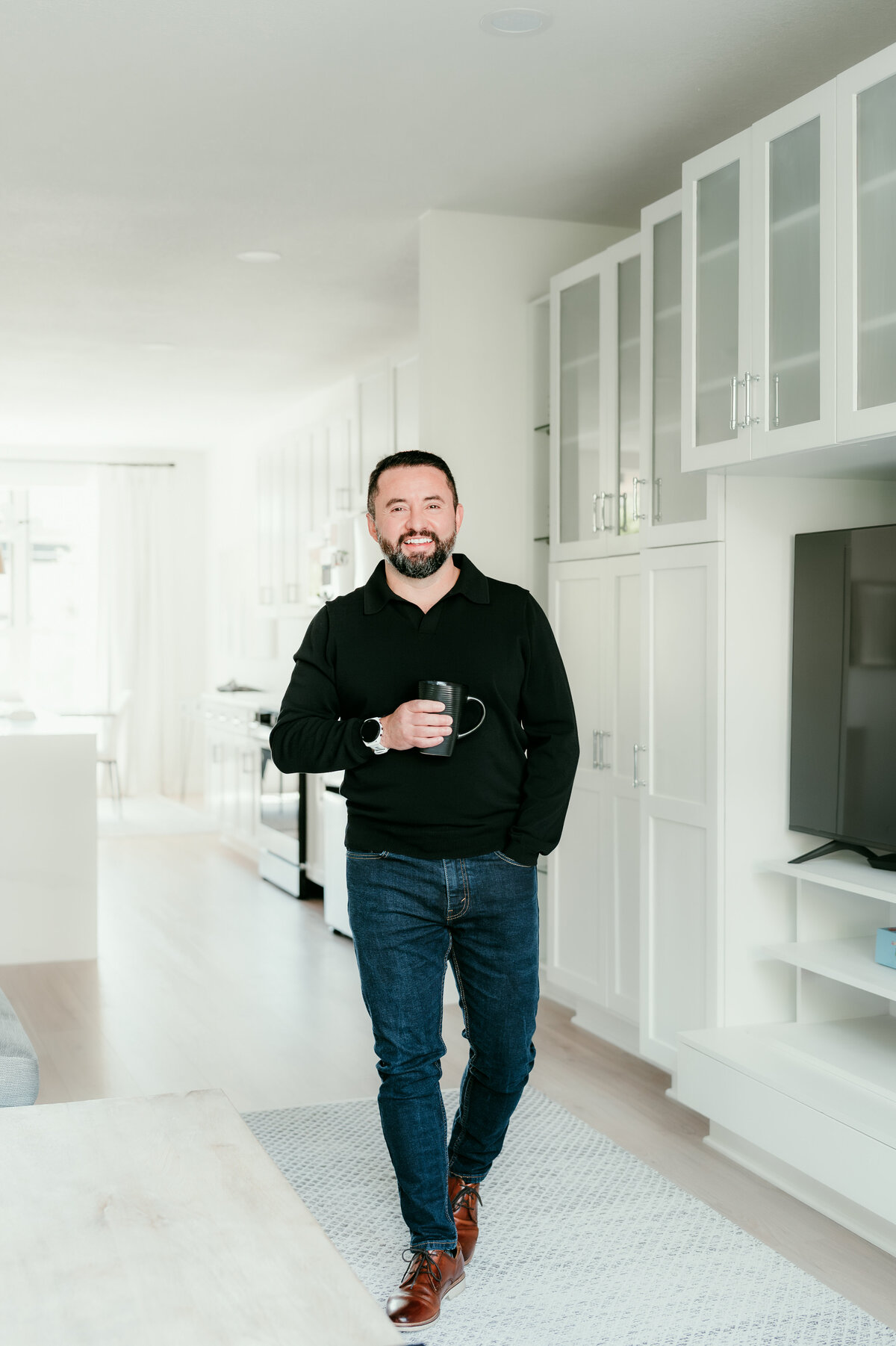 A relaxed man in a black t-shirt and jeans smiling naturally during a professional online dating photo session in Minneapolis, captured by Shannon Kathleen Photography.