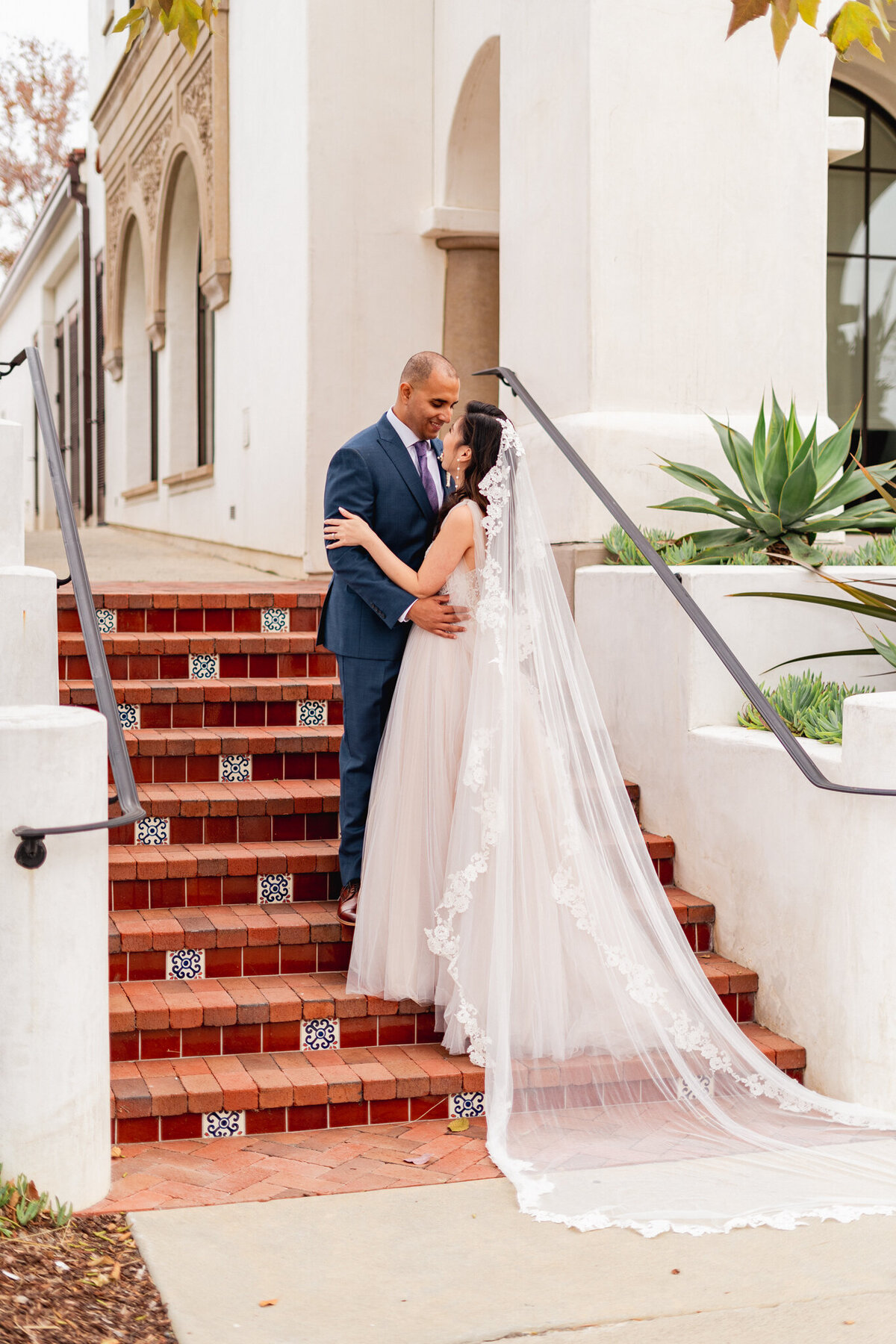 Bride showcases long vail on the steps in Rancho Bernadido