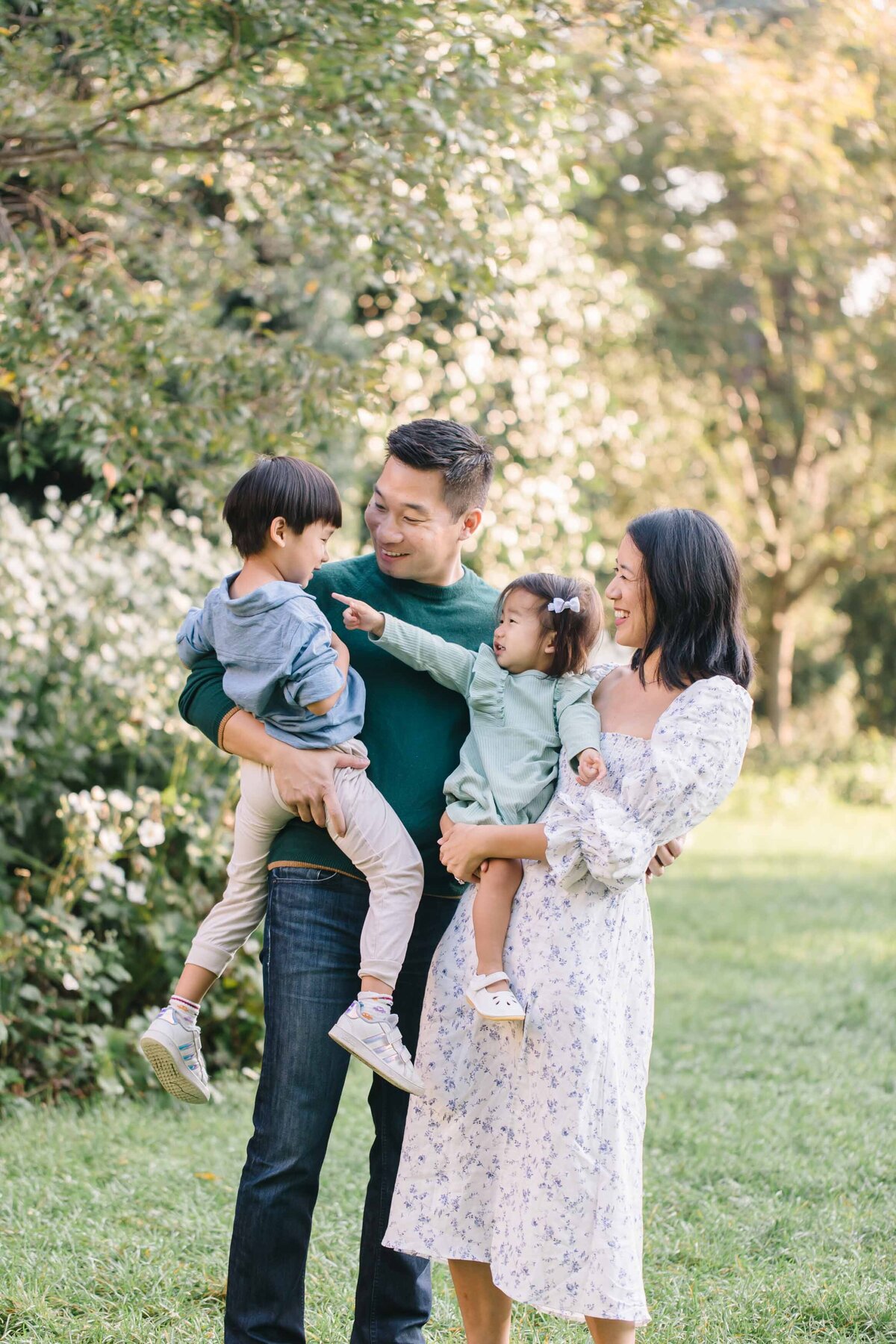 young children being held on parents hips in garden photoshoot