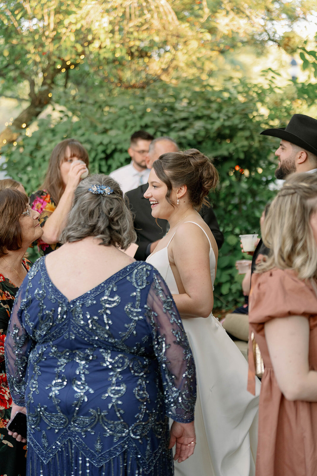 Bride talking with guests during cocktail hour at Café Cortina outdoor patio.