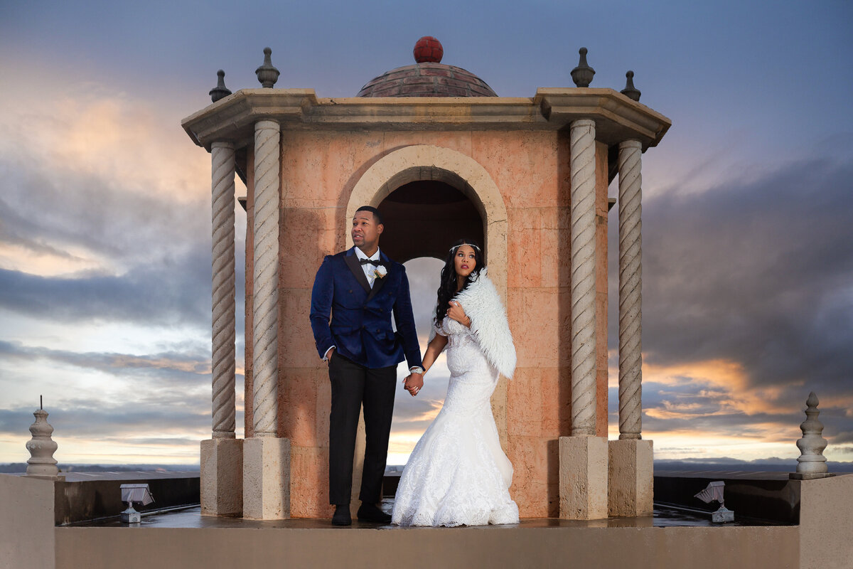 Black bride and groom holding hands at Stoney Ridge Villa on rooftop during sunset