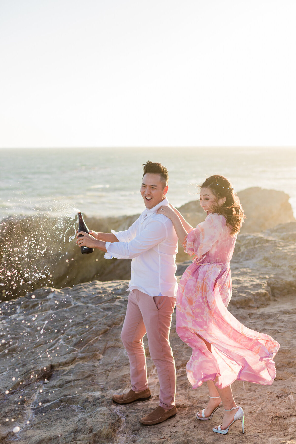 groom pops champagne and bride cheers