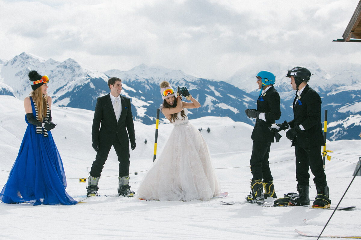 Wedding couple surrounded by friends on skis during fun post-wedding session in Kitzbühel – winter celebration by Studio Rose