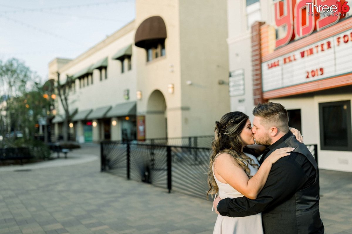 Engaged couple share a kiss in front of the Yost Theater