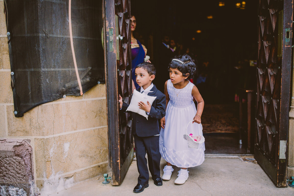 Cute children ring bearer and flower girl looking outside the church on the indian christian wedding day