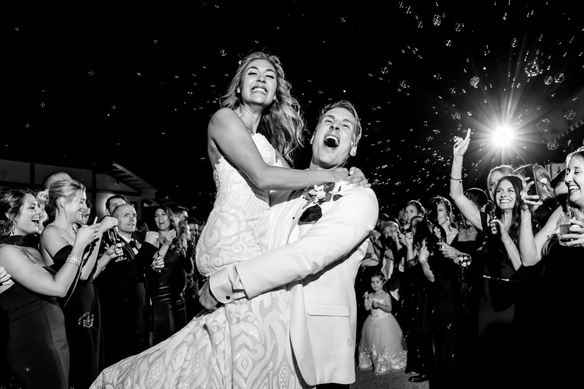 Classy bride and groom sharing an intimate moment with their guests as they leave the wedding reception, representing timeless elegance.