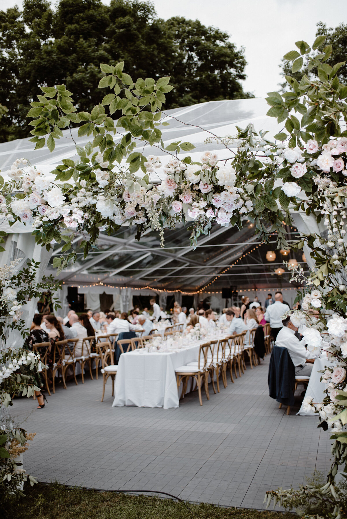A lush installation of flowers frames the entrance to a wedding reception in a tent near Montreal. 