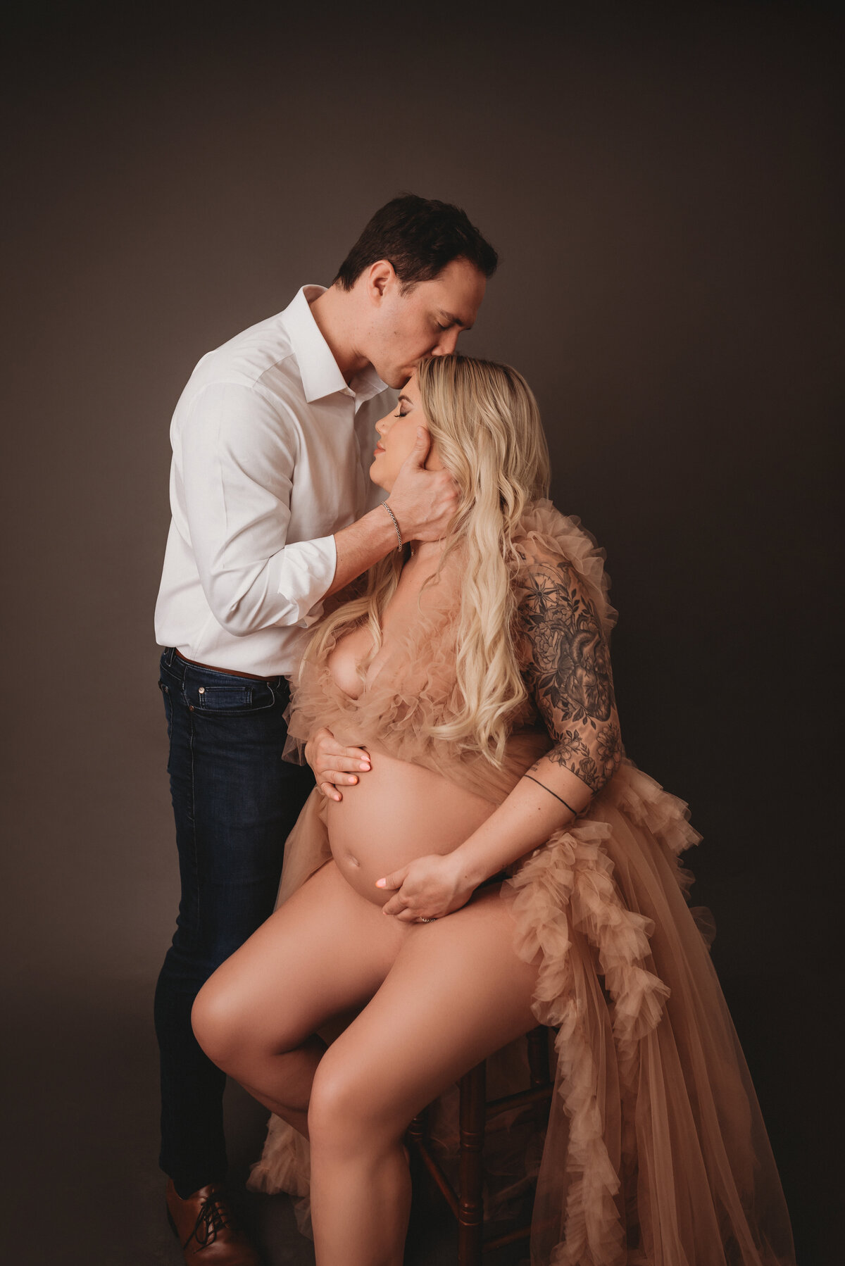 Atlanta, Georgia newborn photographer portrait session with pregnant woman at maternity session posing with husband wearing pink tulle ruffle gown showing off baby bump