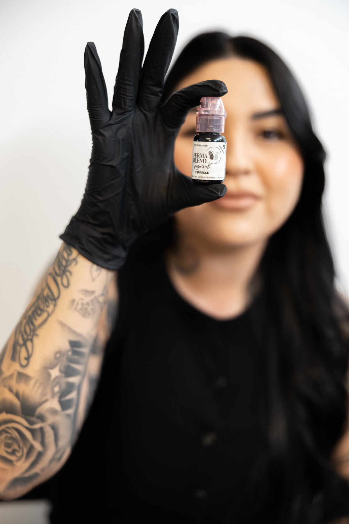 Close-up portrait of hairstylist with tattoos smiling in a studio session. Photograph by Yucaipa branding photographer Kaitlyn Dawn Photography.