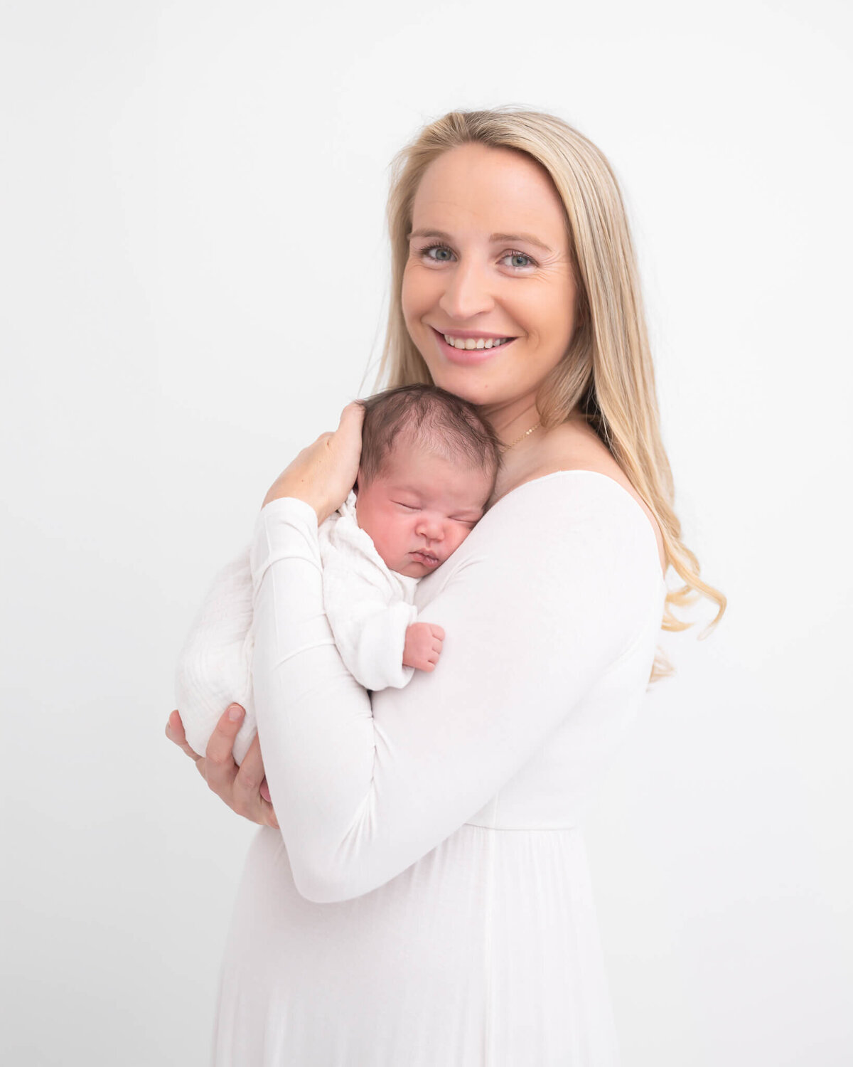 Mom and newborn both in white against white backdrop captured by Allison Amores Photography