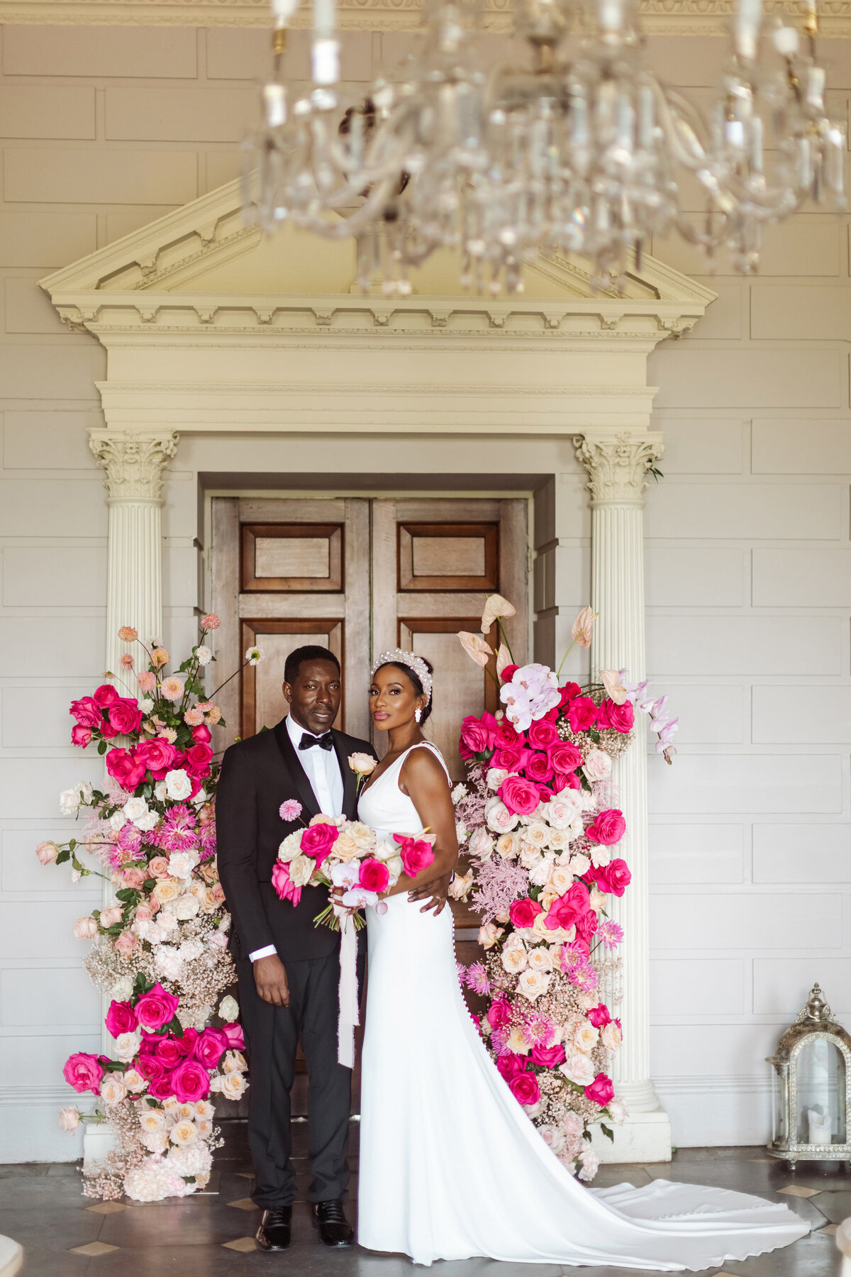 bride and groom by hot pink floral arch