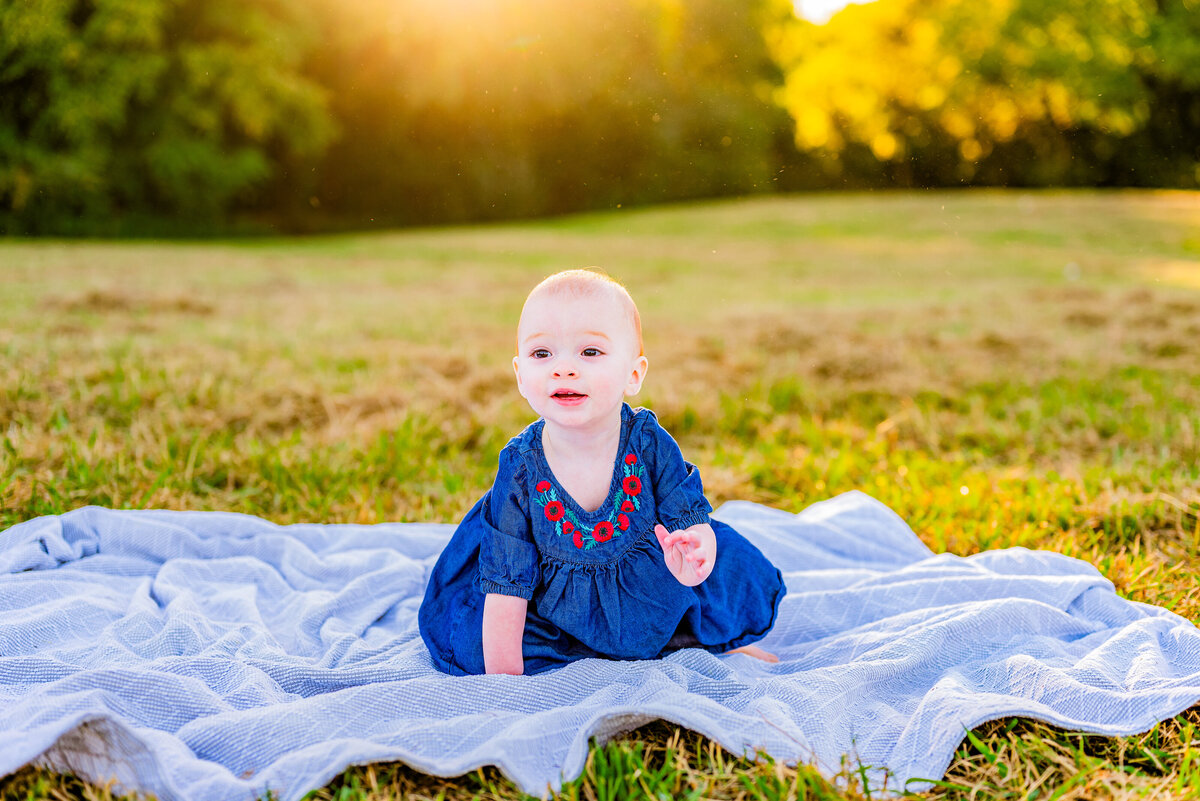 A toddler sits on a blanket at Hayes NAture Preserve