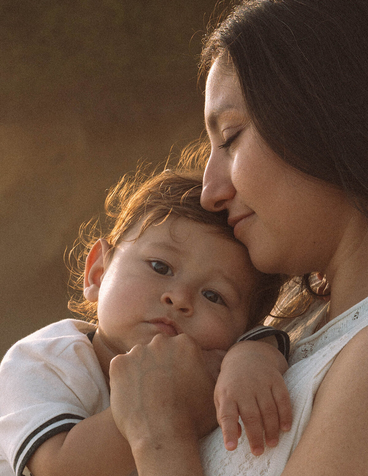 Sweet candid of mom snuggling her baby at Shaw’s Cove in Laguna Beach family photography session.