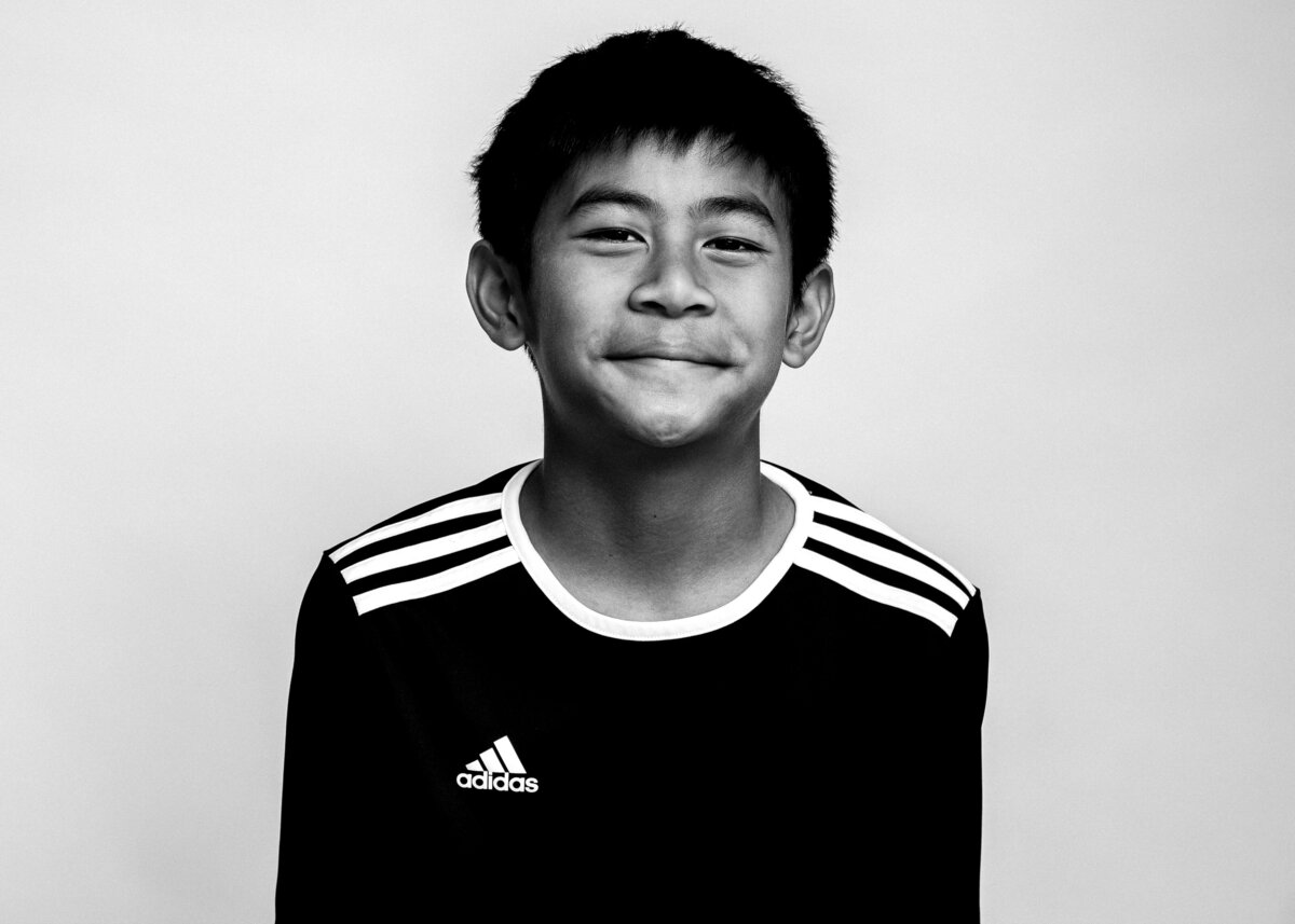 Black and white studio portrait of Jaxon Arruejo, a young soccer player smiling confidently in an Adidas jersey. Holly Springs NC 2025
