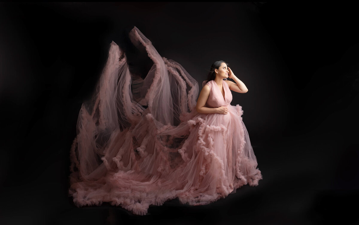 Brown-haired woman wearing a pink maternity dress for her studio maternity photos