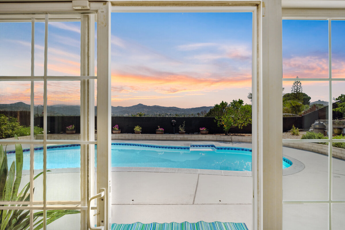 Twilight looking out the glass sliding door to the pool and the mountains in the distance.