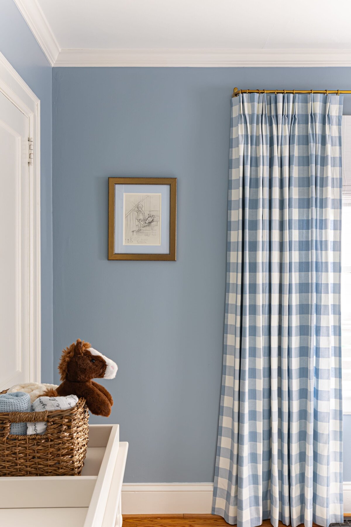 melinda chesson interiors bay street nursery with blue and white checkered curtains and gold framed pencil drawing on wall